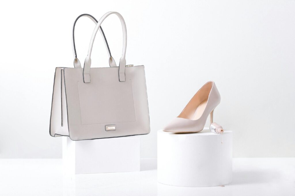 Stylish white leather handbag and heel on white background, highlighting elegance and simplicity.